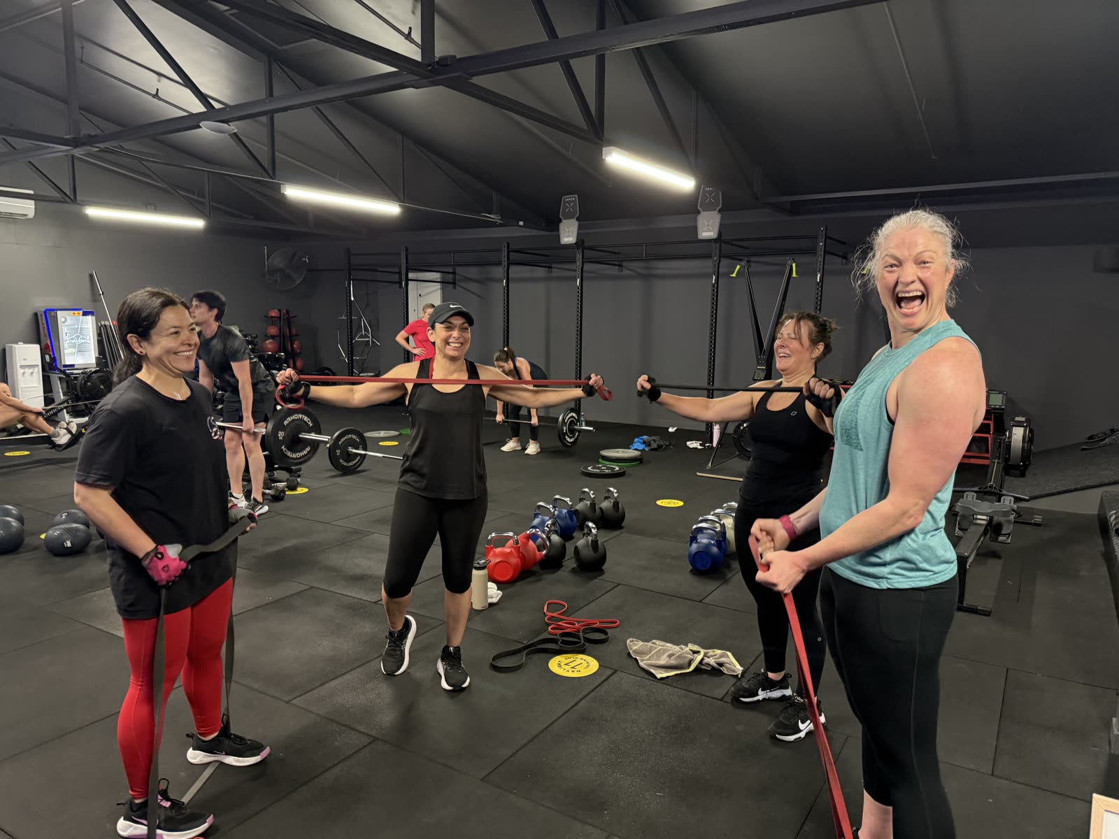 Daylight Training Club members training with resistance bands and laughing during a class